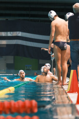 Viertelpause mit der Mannschaft des DSV98 am Beckenrand im Vordergrund Wasserballwart Achim Baran